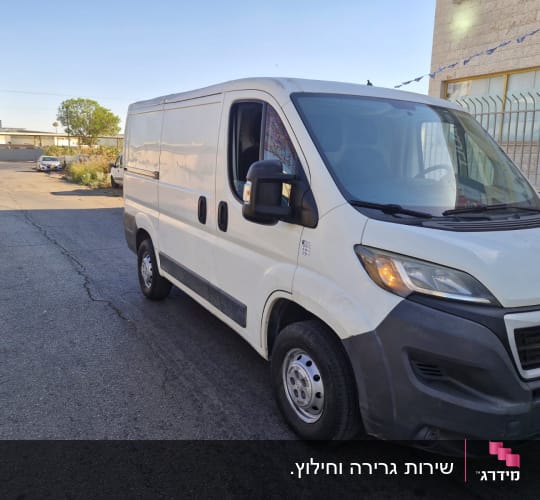 רכב מסחרי לבן חונה ברחוב ליד בניין